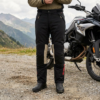 Motorrijder met zwarte BMW GS Puna GTX motorbroek naast een adventuremotor